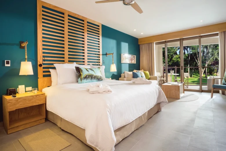 Junior Suite Tropical View with king bed and balcony overlooking lush greenery at Dreams Natura Resort & Spa.