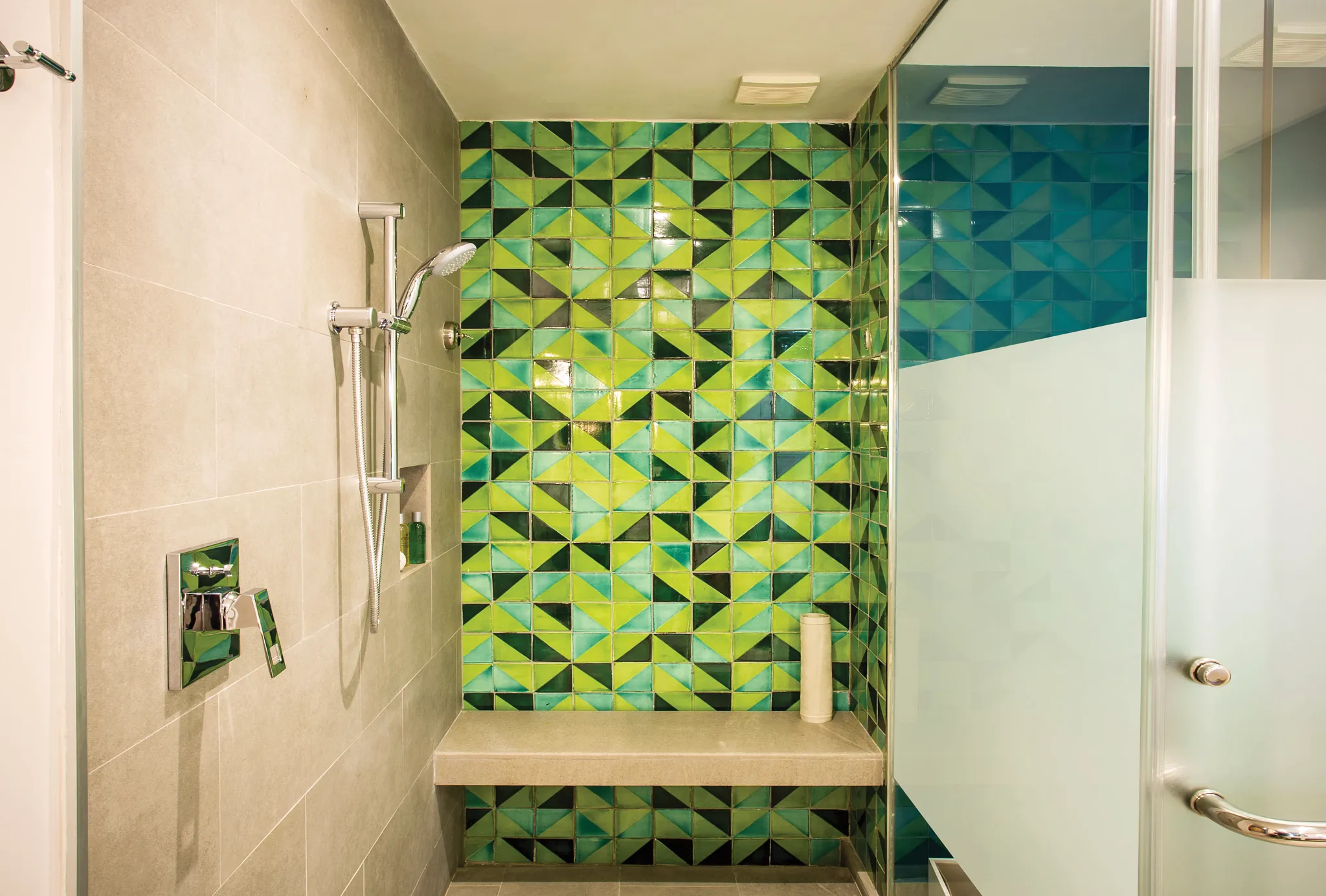 Junior Suite Tropical View shower with green mosaic tile wall and glass enclosure at Dreams Natura Resort & Spa.