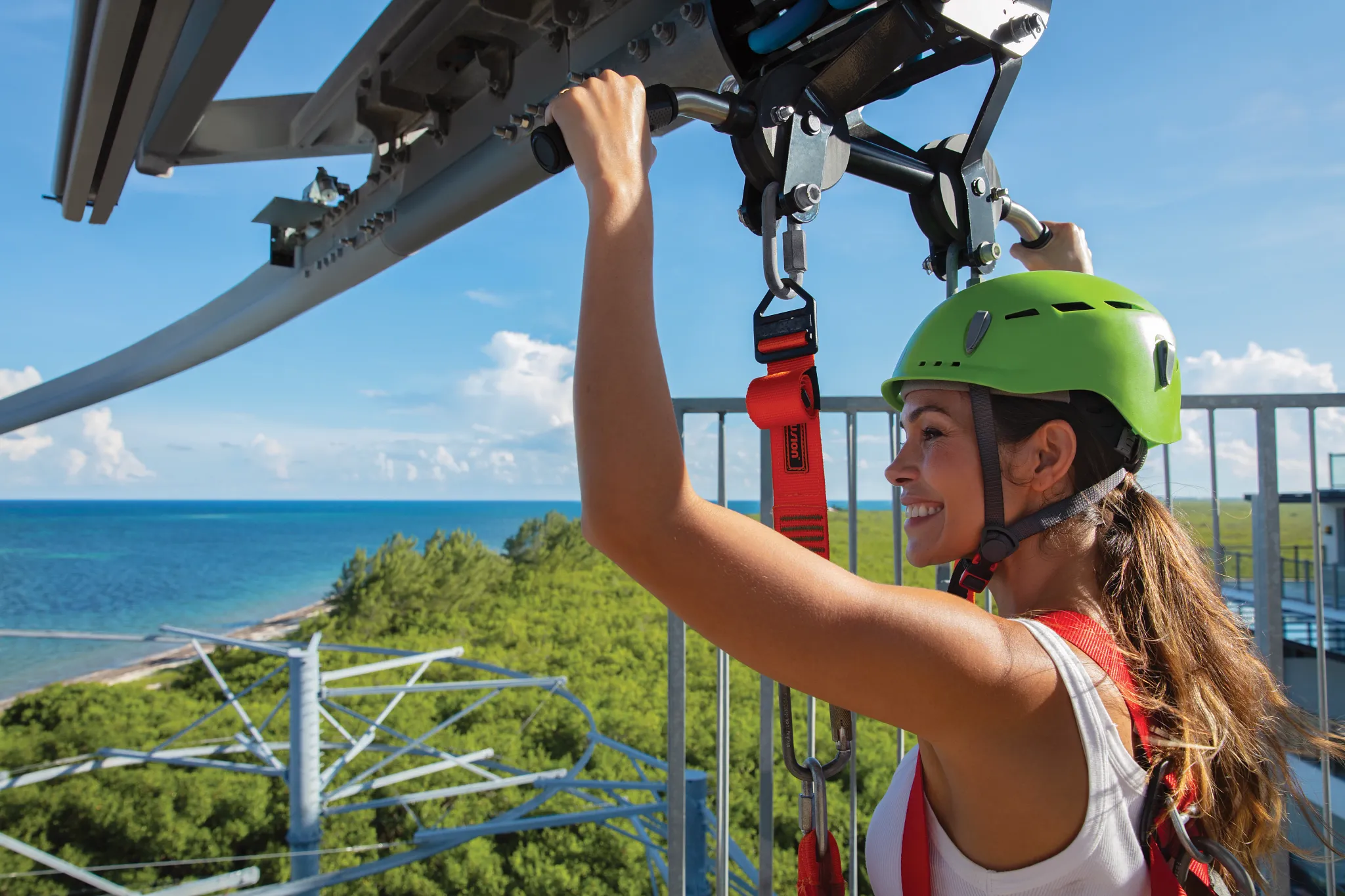 Woman wearing helmet on rollglider zipline with ocean views at Dreams Natura Resort & Spa.